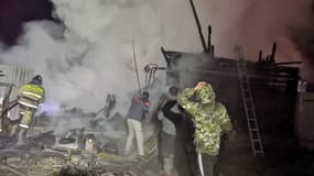 Des hommes et un pompier sur le site d'un incendie dans une maison de retraite du village d'Ishbuldino dans la région du Bachkortostan en Russie centrale, le 15 décembre 2020. 