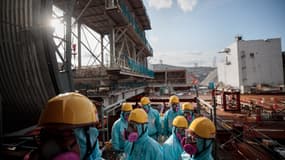 Sur cette photo prise le 31 janvier 2018, des employés de Tokyo Electric Power Company (TEPCO) se tiennent devant le réacteur numéro 3 de la centrale nucléaire de Fukushima Daiichi à Okuma, dans la préfecture de Fukushima.