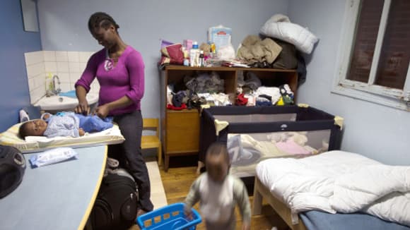 Une femme et ses enfants dans une chambre réservée aux familles à la rue, en banlieue parisienne.