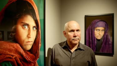 Le photographe Steve Mccurry à côté du portrait de Sharbat Gula, arrêtée au Pakistan.