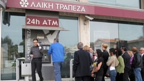 "Des étrangers et des Chypriotes font la queue pour retirer de l'argent devant un distributeur de la Laiki Bank, dans le centre de la capital Nicosie, le 21 mars 2013.