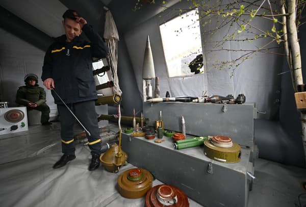 Un soldat ukrainien montrant des mines et des explosifs laissés par les troupes russes dans la zone de Tchernobyl, le 26 avril 2022
