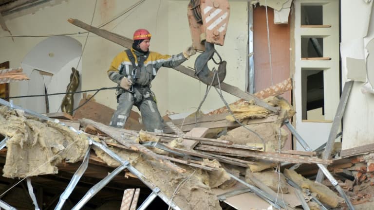 Un membre des équipes de secours dans les décombres d'un immeuble détruit par un bombardement à Kharkiv, le 16 mars 2022 en Ukraine