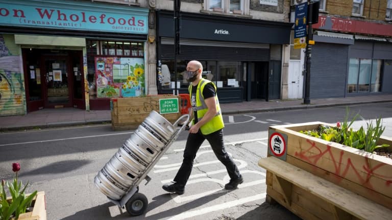 Un homme livre de la bière dans un pub de Londres en prévision de l'allègement des restrictions sanitaires le 9 avril 2021