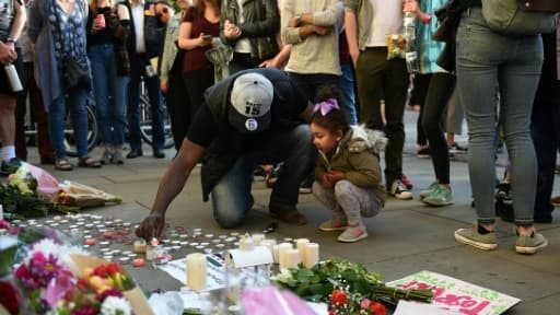 Un homme et sa petite fille allument des bougies à quelques pas du lieu de l'attentat à l'Albert Square de Manchester le 23 mai 2017
