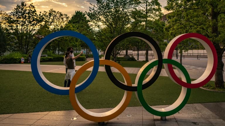 Des gens prennent des photos avec les anneaux olympiques, à côté du musée des Jeux Olympiques à Tokyo, le 17 mai 2021 