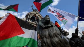 Des manifestants brandissent des drapeaux palestiniens en grimpant sur le Monument à la République lors d'une manifestation appelant à la paix à Gaza, place de la République à Paris, le 22 octobre 2023.