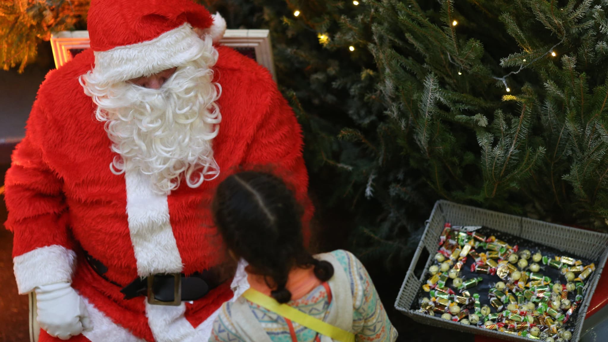 Un père Noël en train de distribuer des bonbons à une fillette.