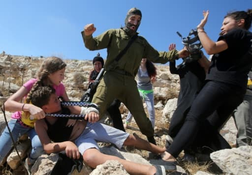 Un soldat israélien plaque un enfant palestinien sur un rocher lors d'affrontements entre les forces de sécurité israéliennes et des manifestants palestiniens, le 28 août 2015 à Nabi Saleh près de Ramallah en Cisjordanie
