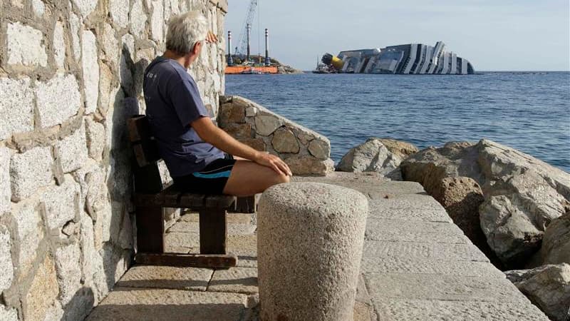 L'épave du Costa Concordia, vue depuis le port du Giglio. Six mois après le naufrage du paquebot au large de la Toscane, une cérémonie a été organisée vendredi en mémoire des victimes sur la petite île du Giglio. Les cloches de l'église ont sonné à 21h42,