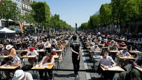 Des milliers de personnes de dix ans à 92 ans participent à une dictée géante sur l'avenue des Champs-Elysées à Paris, le 4 juin 2023 