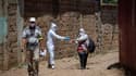 Un membre d'une équipe médicale marocaine désinfecte les mains d'une femme testée positive au nouveau coronavirus, au nord de Rabat, le 20 juin 2020.
