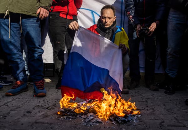 Un manifestant brûle un drapeau russe à Varsovie lors d'un rassemblement contre la guerre en Ukraine, le 24 février 2022