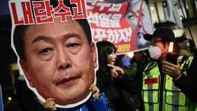 Un manifestant tient un carton sur lequel est écrit « Chef des insurgés » sur une image représentant le visage du président sud-coréen Yoon Suk Yeol. La scène a lieu lors d'une manifestation appelant à son éviction devant le Parlement de Séoul. Le 8 décembre 2024. (Photo d'illustration)