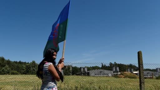 Sur cette photo du 24 juin 2017, une protestataire brandit un drapeau rom devant la porcherie de Lety, construite dans les années 1970 sur le site d'un ancien camp nazi