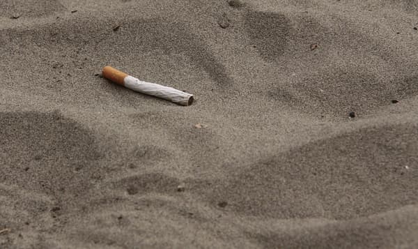 Un mégot de cigarette dans le sable.