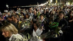 Une chaîne humaine déplace les bouquets déposés sur la Promenade des Anglais en hommage aux victimes de l'attentat du 14 juillet vers le front de mer à Nice le 18 juillet 2016