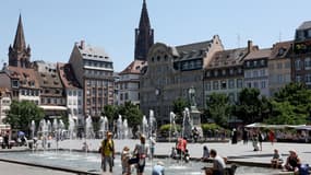 Des habitants et des touristes se rafraîchissent à la fontaine de la place Kléber à Strasbourg.
