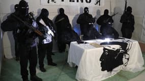 Des membres du Front de Libération Nationale Corse (FLNC), cagoulés, vêtus de treillis militaires et armés de fusils, tiennent une conférence de presse dans un lieu tenu secret sur l'île méditerranéenne française de Corse en janvier 2024.