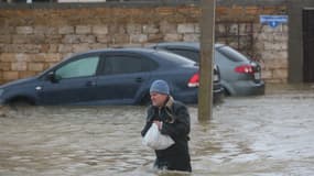 Un homme marche dans une rue inondée lors de l'évacuation des habitants du village de Pribrezhnoe en Crimée, le 27 novembre 2023, à la suite d'une tempête.