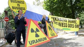 Des militants écologistes de Greenpeace brandissent des pancartes, un drapeau russe, de faux panneaux de signalisation et une statue de cire du président français Emmanuel Macron - qu'ils disent avoir volée au musée Grévin - lors d'une action contre les importations françaises de gaz et d'engrais en provenance de Russie, devant l'ambassade de Russie à Paris, le 2 juin 2025.
