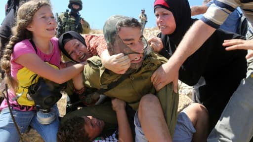 Un soldat israélien plaque un enfant palestinien sur un rocher lors d'affrontements entre les forces de sécurité israéliennes et des manifestants palestiniens, le 28 août 2015 à Nabi Saleh près de Ramallah en Cisjordanie Un soldat israélien plaque un enfant palestinien sur un rocher lors d'affrontements entre les forces de sécurité israéliennes et des manifestants palestiniens, le 28 août 2015 à Nabi Saleh près de Ramallah en Cisjordanie