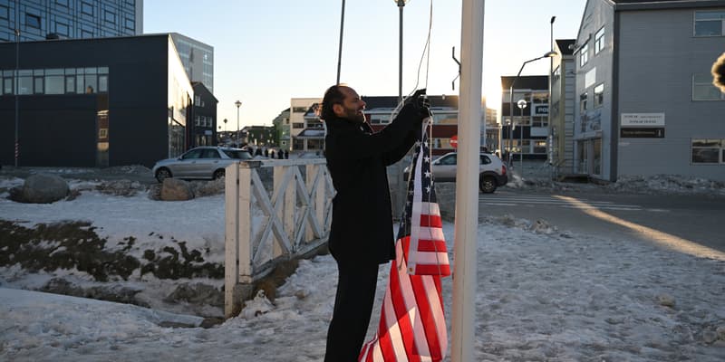 Le comédien allemand Maxi Schafroth tente de hisser un drapeau américain dans la ville de Nuuk, dans l'ouest du Groenland, le 28 janvier 2026. 