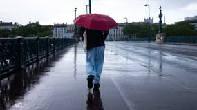Un homme sous un parapluie au-dessus des berges du Rhône, à Lyon, le samedi 3 mai 2025.