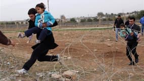 Des Syriens fuyant des combats à la frontière avec la Turquie dans la ville de Ceylanpinar. Selon le Haut Commissariat des Nations unies pour les réfugiés, quelque 9.000 Syriens ont franchi cette frontière ces dernières 24 heures, ce qui porte à plus de 1