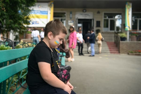 Un enfant assis devant une école lors d'une cérémonie d'ouverture après la reconstruction de l'établissement à la veille de la rentrée scolaire à Boutcha, en Ukraine, le 31 août 2022