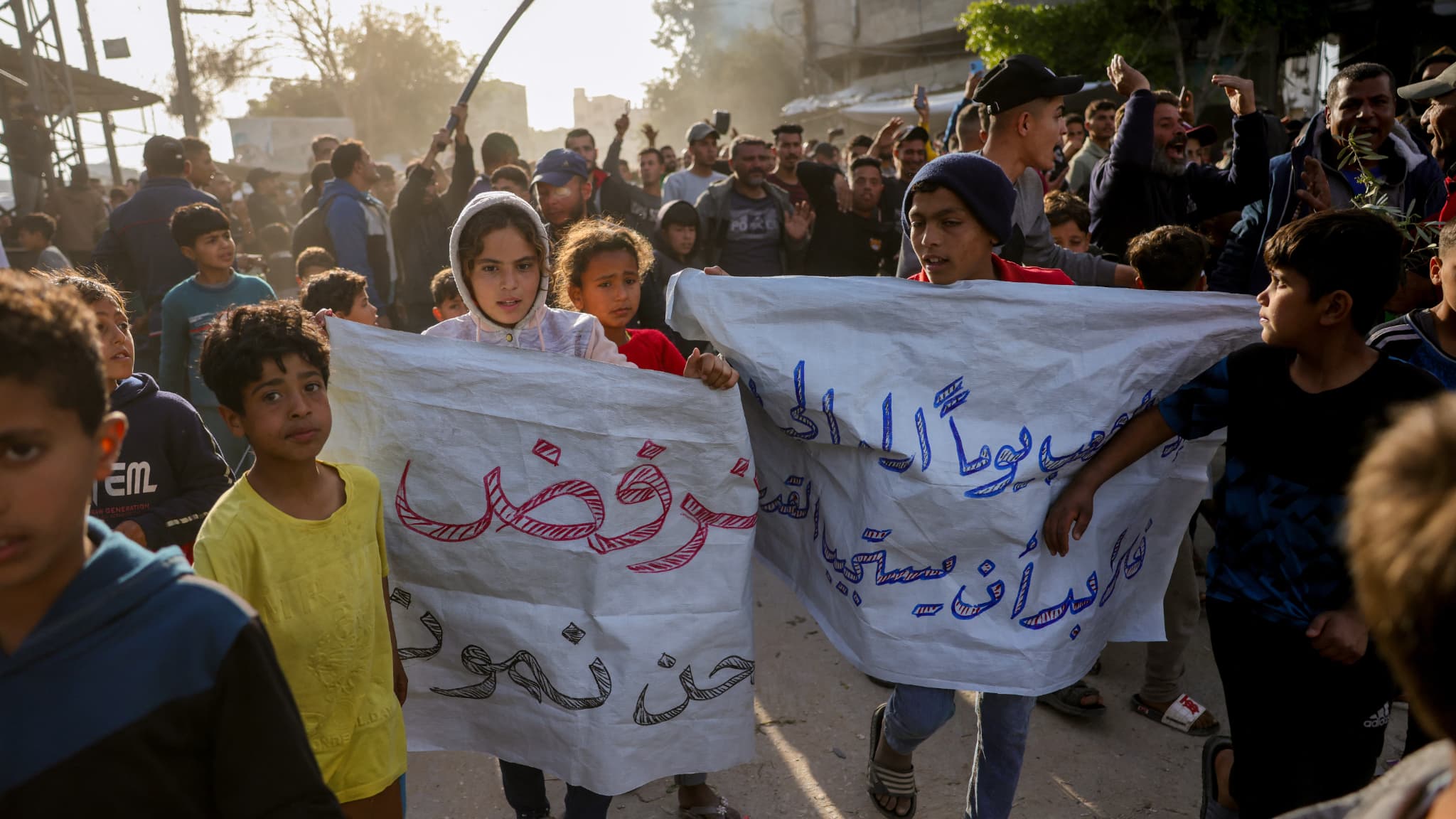 Des enfants portent des pancartes sur lesquelles on peut lire en arabe: "Nous refusons de mourir" lors d'un rassemblement appelant à la fin de la guerre, à Beit Lahia, dans le nord de la bande de Gaza, le 25 mars 2025.