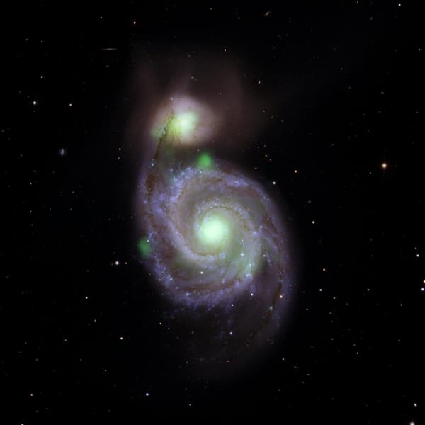 Des sources vertes brillantes de rayons X à haute énergie capturées et superposées sur une image optique de la galaxie Whirlpool (la spirale au centre de l'image) et de sa galaxie compagne, M51b (la brillante au-dessus du Whirlpool). 