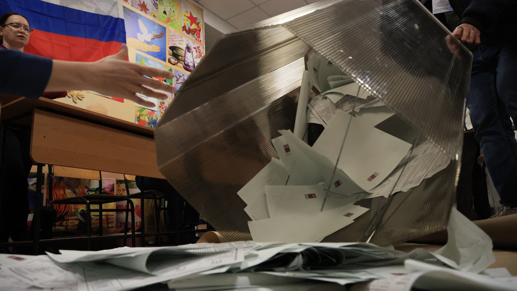 Des membres d'une commission électorale locale vident une urne dans un bureau de vote après la fermeture des bureaux de l'élection présidentielle russe à Simferopol, en Crimée, le 17 mars 2024.
