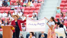 La présidente brésilienne Dilma Rousseff (g) et une dirigeante de la Confédération des travailleurs agricoles déploient un drapeau lors de la clôture de la marche des femmes des zones rurales, le 12 août 2015 à Brasilia