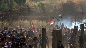 Des manifestants palestiniens et syriens fuient pour s'abriter des gaz lacrymogènes tirés par les soldats israéliens dimanche sur le plateau du Golan, près de la frontière entre la Syrie et Israël. La Syrie a porté lundi à 23 morts le bilan de cette manif