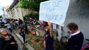Une femme brandissant une affiche "mais que fait la police?" devant le domicile de Sandra P., ce dimanche.