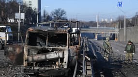 Des militaires ukrainiens en poste à côté de l'un de leurs camions brûlés, après un combat avec des forces russes, dans l'Ouest de la capitale Kiev, samedi 26 février 2022