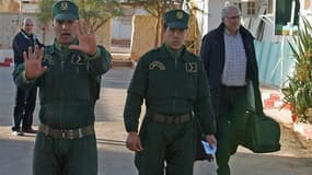 Des gendarmes algériens escortent un otage norvégien libéré au poste de police d'In Amenas, samedi. Selon le ministre algérien de la Communication, Mohamed Said, plus de 23 otages ont été tués lors de la prise d'otages qui a pris fin samedi dans le comple