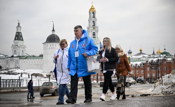 Des membres de la commission électorale marchent pour rendre visite aux électeurs à leur domicile lors de l'élection présidentielle russe à Sergiyev Posad, au nord-est de Moscou, le 16 mars 2024.