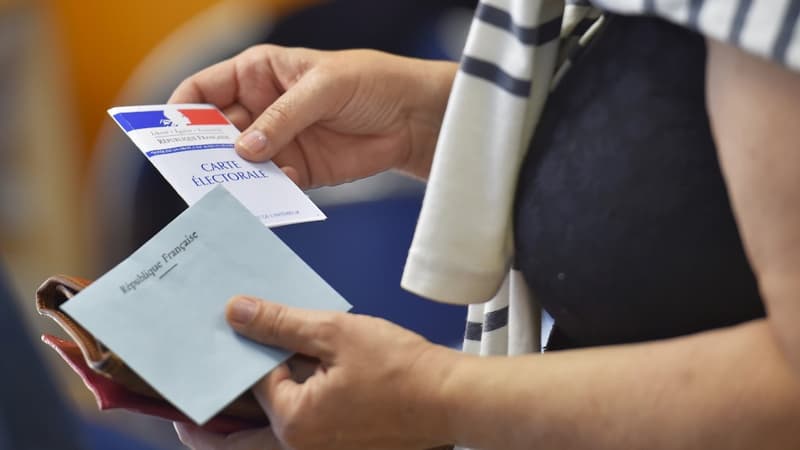 Une femme, carte électorale et enveloppe de vote à la main (Photo d'illustration).