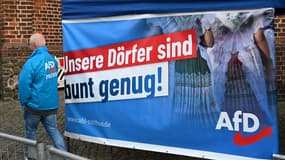 Un représentant du parti AfD passe devant une bannière électorale portant l'inscription "Nos villages sont assez colorés" avant un rassemblement pour les élections régionales à Cottbus dans l'État de Brandebourg en Allemagne de l'Est, le 19 septembre 2024.