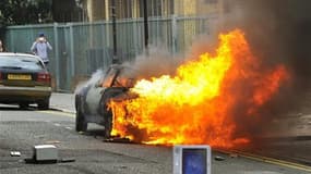 véhicule en feu lundi après-midi à Hackney, dans l'est de Londres. Des violences ont à nouveau éclaté, pour le troisième jour consécutif, dans la capitale britannique, opposant jeunes gens et policiers. /Photo prise le 8 août 2011/REUTERS/Toby Melville