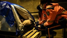 Des bénévoles de la protection civile s'adressent à un sans-abri installé dans une tente à Paris, le 9 février 2021 nuit de grand froid