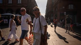 Un couple mange une glace en marchant dans une rue de Toulouse le 12 août 2024, alors que la France connaît sa deuxième canicule de l'année.