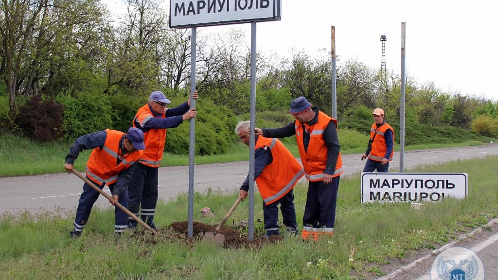 Des employés municipaux changent les panneaux routiers ukrainiens en russes à l'extérieur de la ville de Marioupol le 5 mai 2022