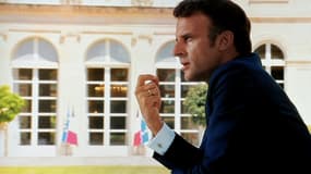 Photo d'un écran télé montrant le président Emmanuel Macron répondant aux questions des journalistes Anne-Claire Coudray (G) et Caroline Roux (D) le 14 juillet 2022 au palais de l'Elysée à Paris