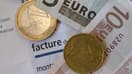 Des billets et des pièces en euros sur une facture EDF