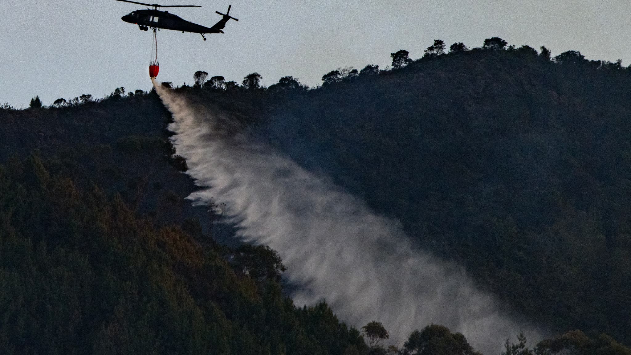 Un hélicoptère de la police colombienne largue de l'eau pour éteindre un feu de forêt à Bogota, le 24 janvier 2024. 