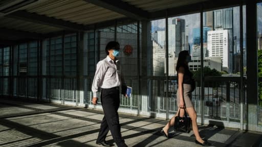 Des habitants de Hong Kong empruntent le 3 juin 2020 une passerelle recouverte de grillage, édifiée par les autorités locales en réponse aux manifestations pro-démocratie.