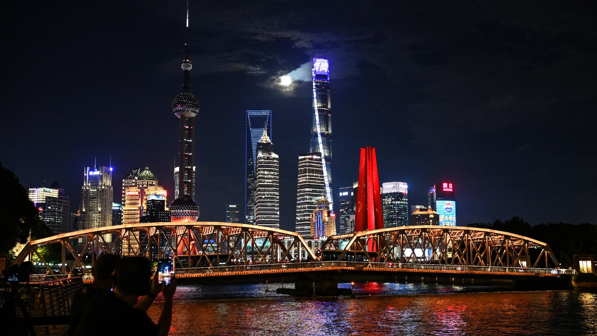 Des personnes prennent des photos de la pleine lune, également connue sous le nom de super lune bleue, dans le quartier financier de Lujiazui à Shanghai, le 19 août 2024.